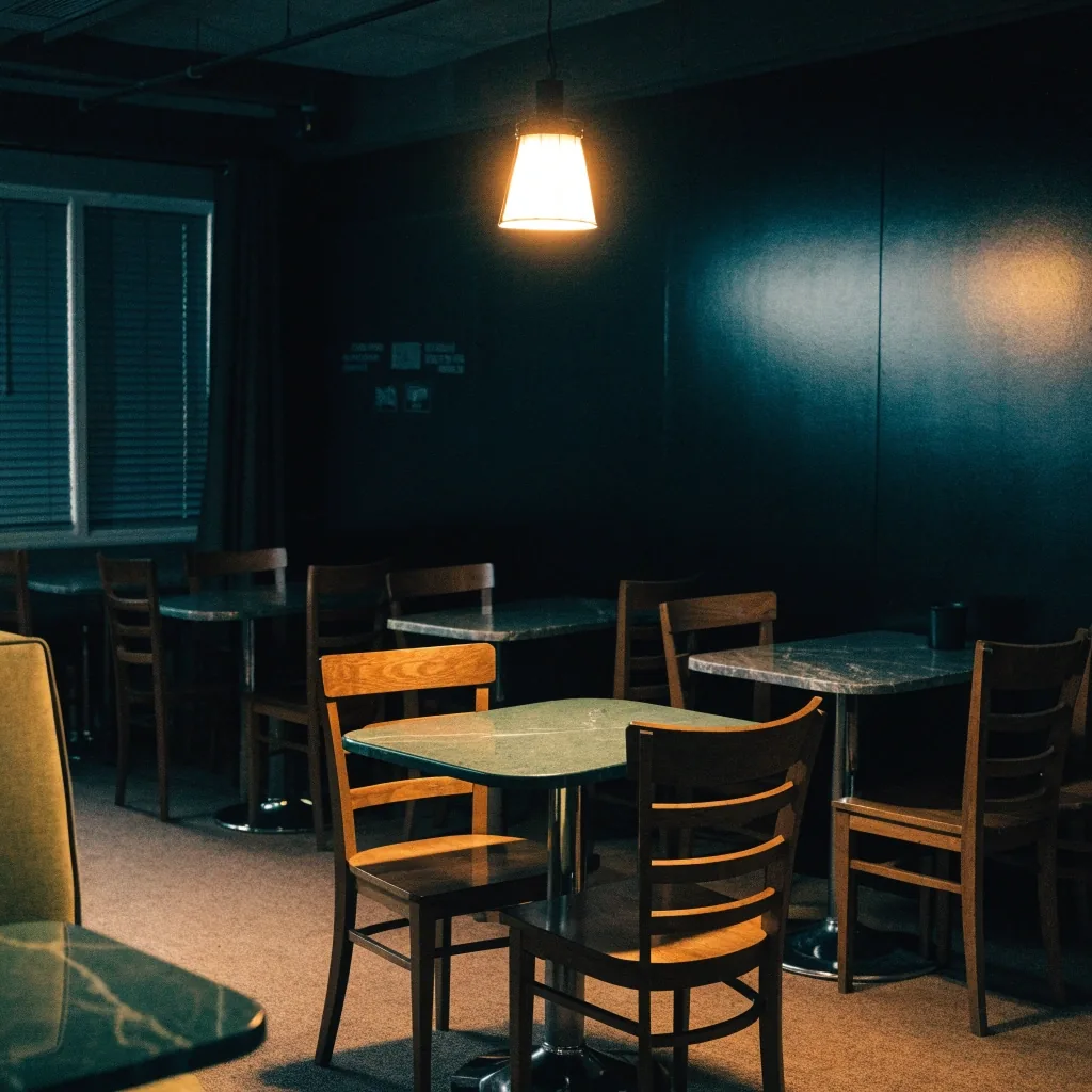 Empty dining room chairs under a single warm light after closing